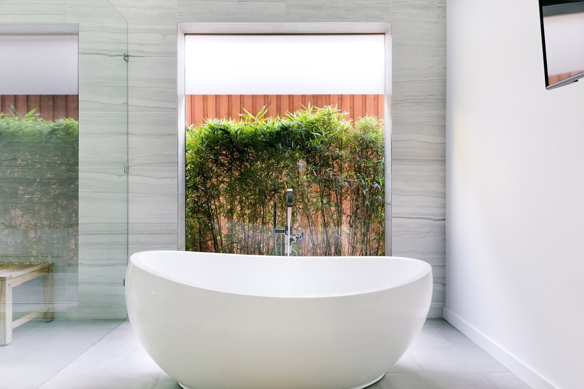 Freestanding white tub beside a garden window