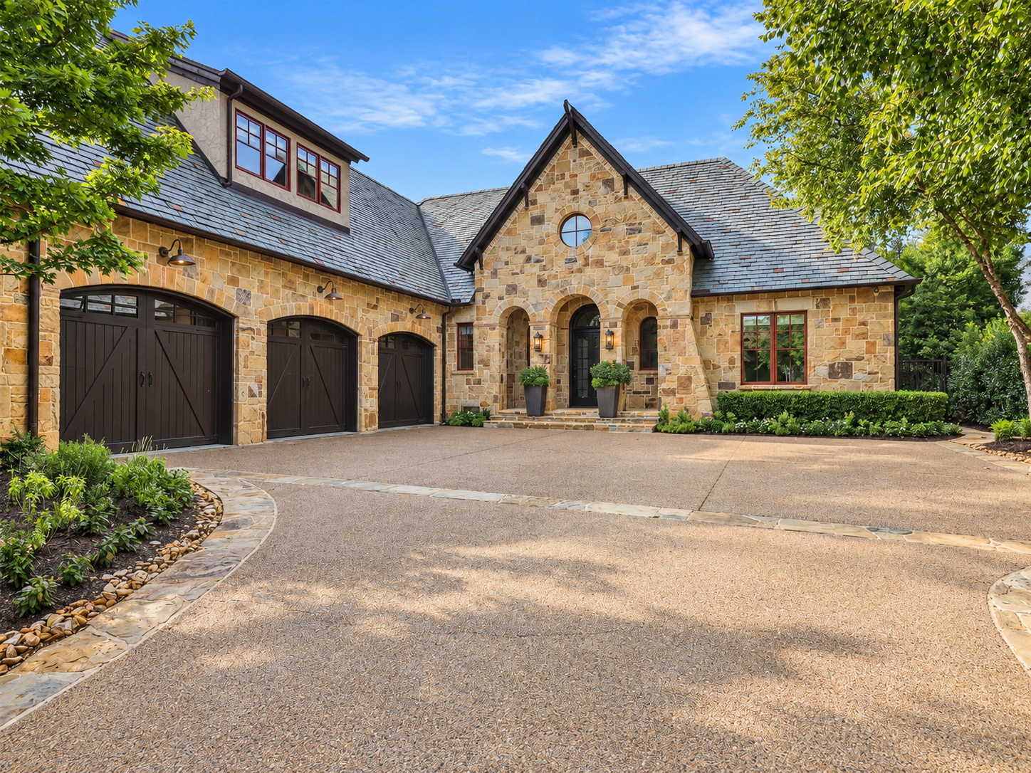 Stone home with slate roof, arched entrance and courtyard driveway