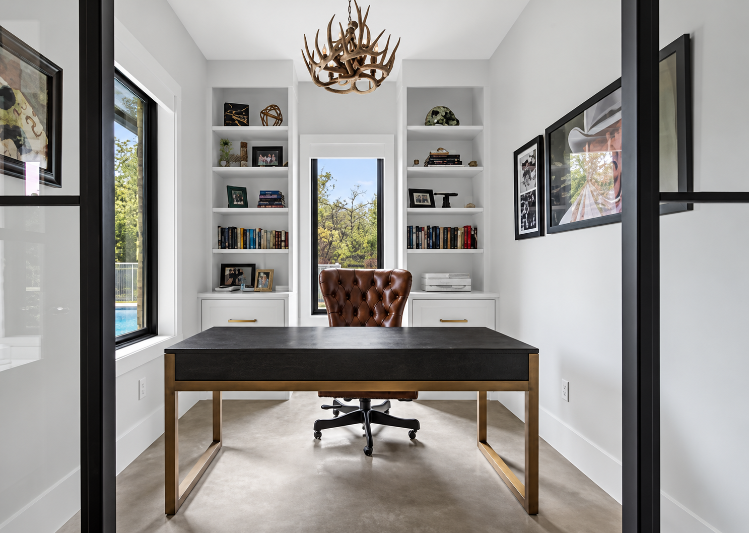 Office desk and built-in shelves below sculptural light fixture