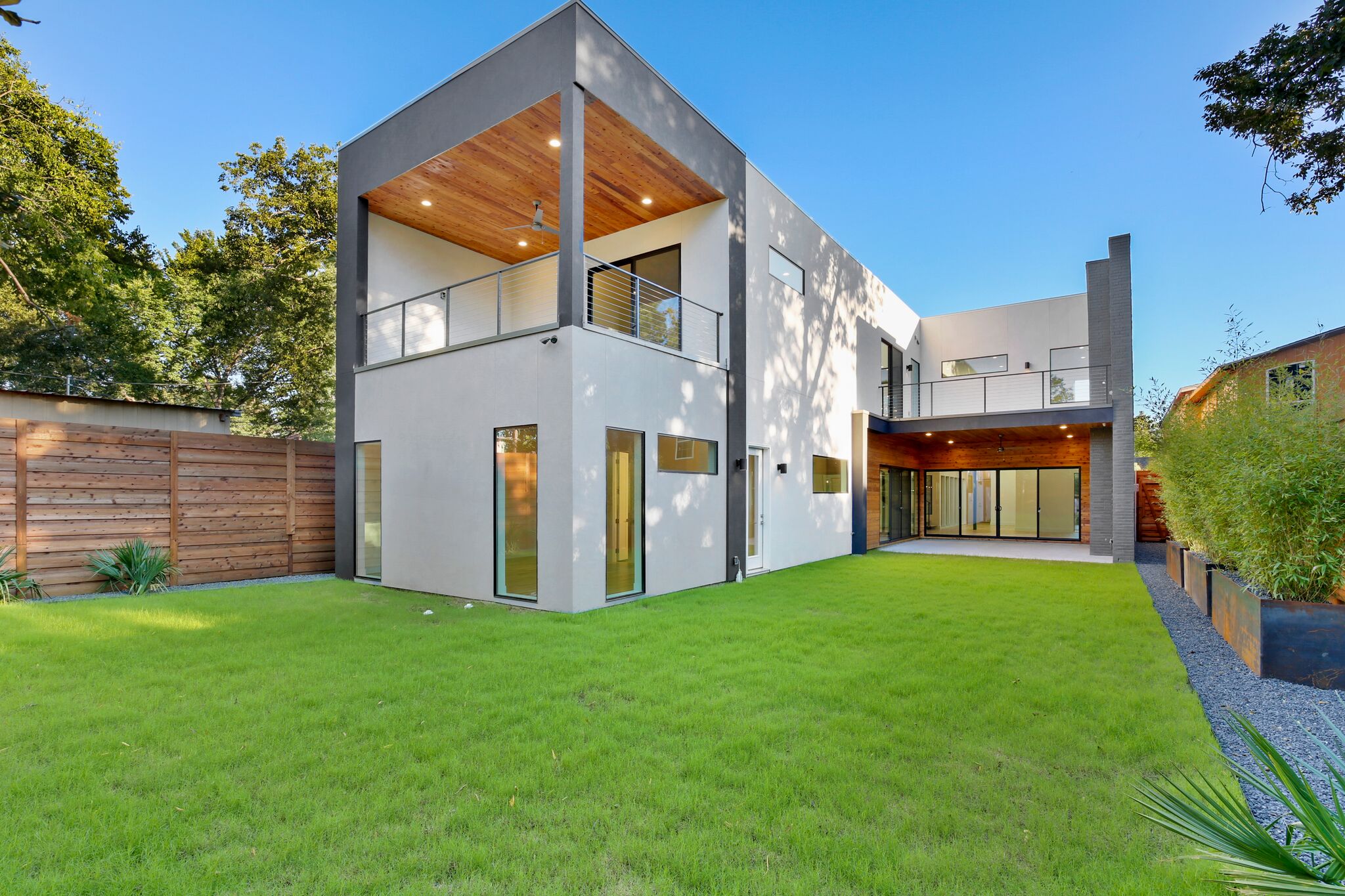 Modern home with balcony overlooking green lawn
