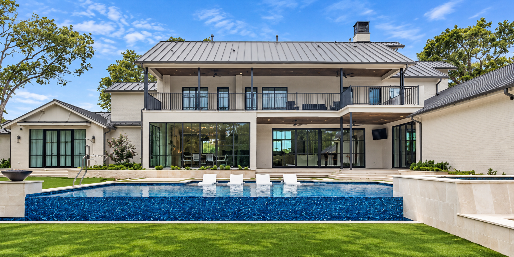 Rear elevation of white home behind a blue pool